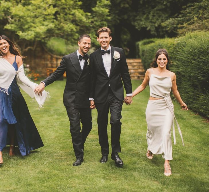 Portrait of Two Groomsmen in Tuxedos with Friends