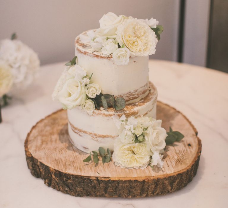 Two Tier Semi Naked Wedding Cake Decorated with White Flowers on Wooden Tree Slice Cake Stand