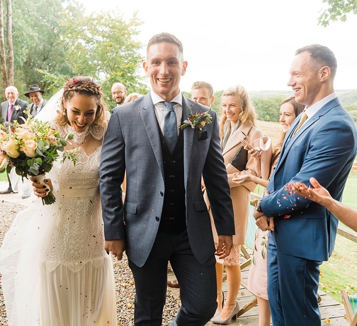 Confetti Throw | Bride in Laced KatyaKatya Wedding Dress with Cap Sleeves and Ribbon Belt | Groom in Blue T.M Lewin Suit with Navy Hawkes Bespoke Outfitters Waistcoat | Bridal Bouquet of Wild Flowers  with Lavender, Thistles, White Roses and Eucalyptus | Lace KatyaKatya Dress for Tipi Wedding at Fforest Farm | Claudia Rose Carter Photography