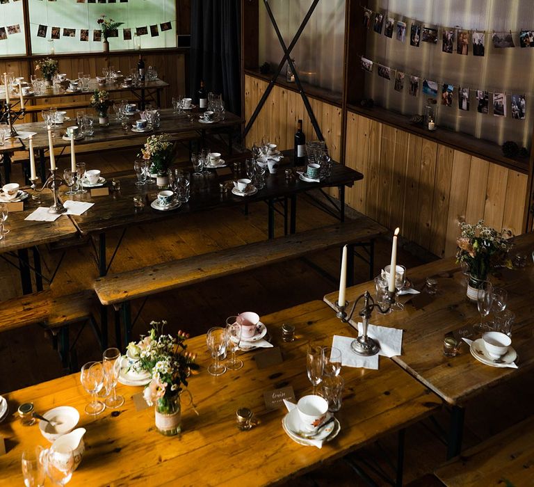 Wedding Reception Decor | On Site Pub at Fforest Farm | Long Wooden Tables and Benches | White Bunting | Flowers in Jam Jars | Tea Cups and Saucers | Candlesticks | Tapered Candles | Lace KatyaKatya Dress for Tipi Wedding at Fforest Farm | Claudia Rose Carter Photography