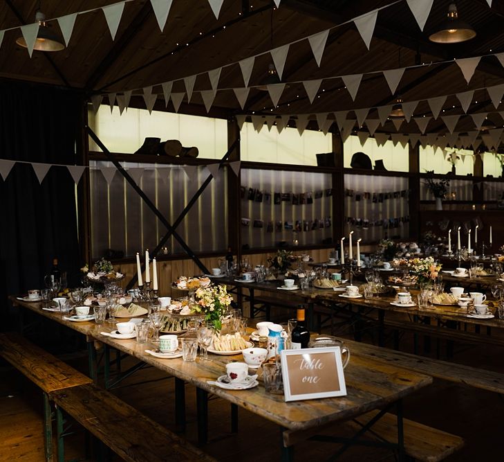 Wedding Reception Decor | On Site Pub at Fforest Farm | Long Wooden Tables and Benches | White Bunting | Flowers in Jam Jars | Tea Cups and Saucers | Candlesticks | Tapered Candles | Lace KatyaKatya Dress for Tipi Wedding at Fforest Farm | Claudia Rose Carter Photography