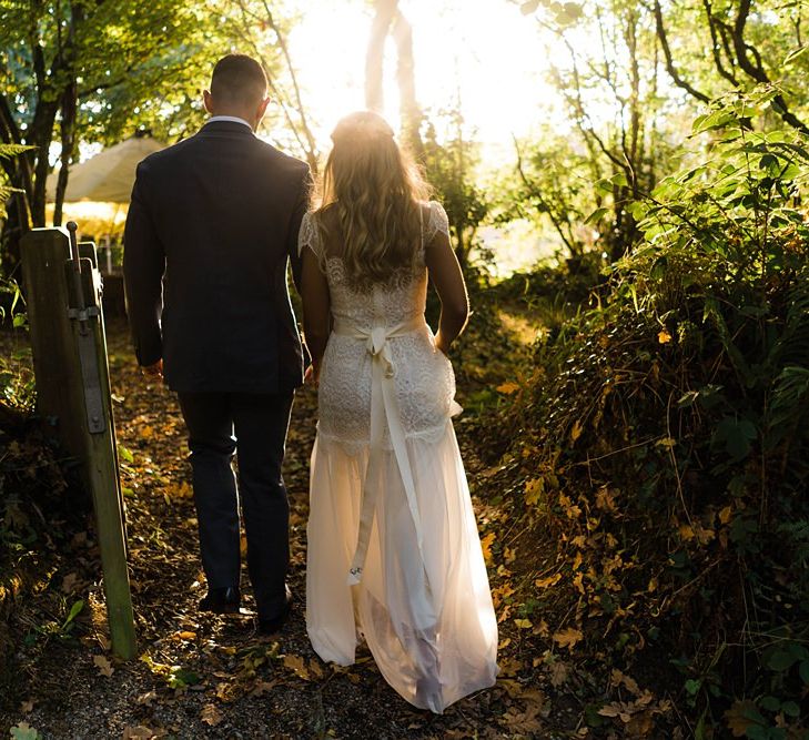 Bride in Laced KatyaKatya Wedding Dress with Cap Sleeves and Ribbon Belt | Groom in Blue T.M Lewin Suit with Navy Hawkes Bespoke Outfitters Waistcoat | Lace KatyaKatya Dress for Tipi Wedding at Fforest Farm | Claudia Rose Carter Photography