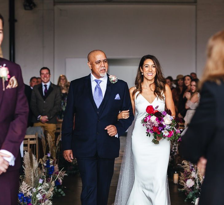 Bride walking down the aisle wearing polka dot Watteau train