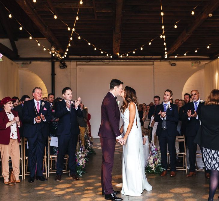 Industrial ceremony with festoon lighting and pink blossom trees