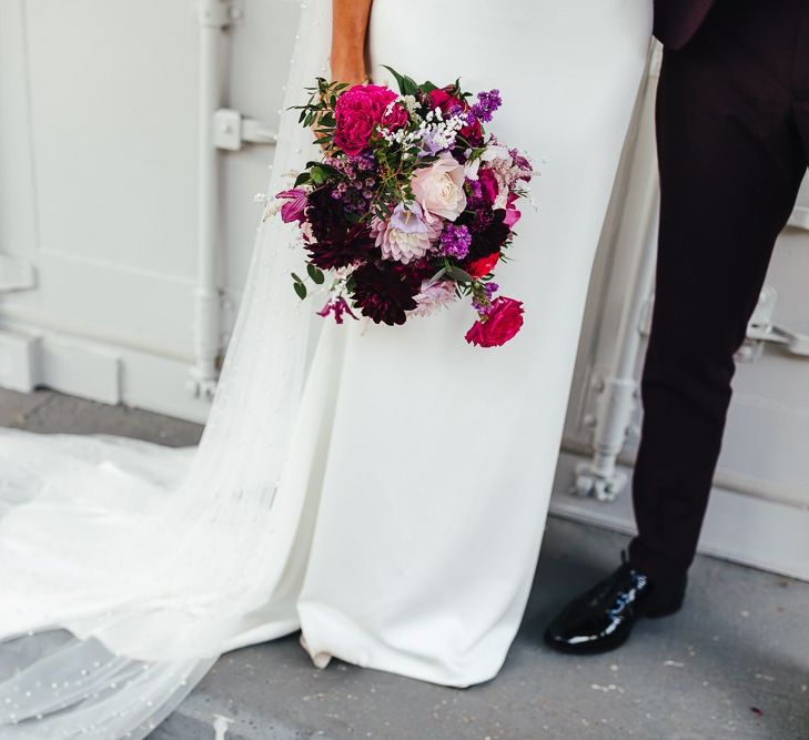 Brides beautiful polka dot embellished Watteau train and vibrant floral bouquet