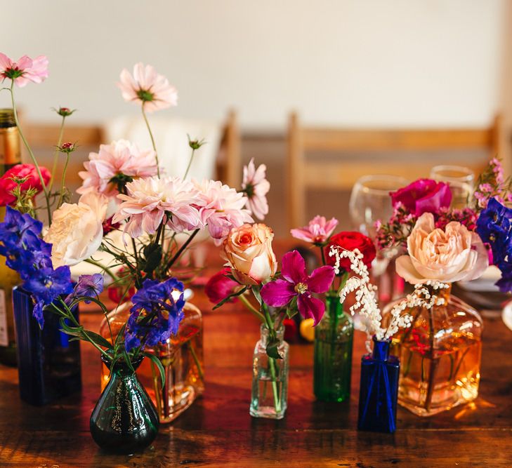 Vibrant floral table arrangements in colourful glass vases at industrial reception in London