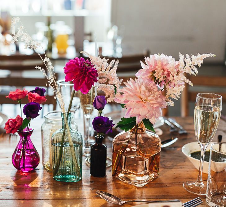 Vibrant floral table arrangements displayed in colourful glass vases