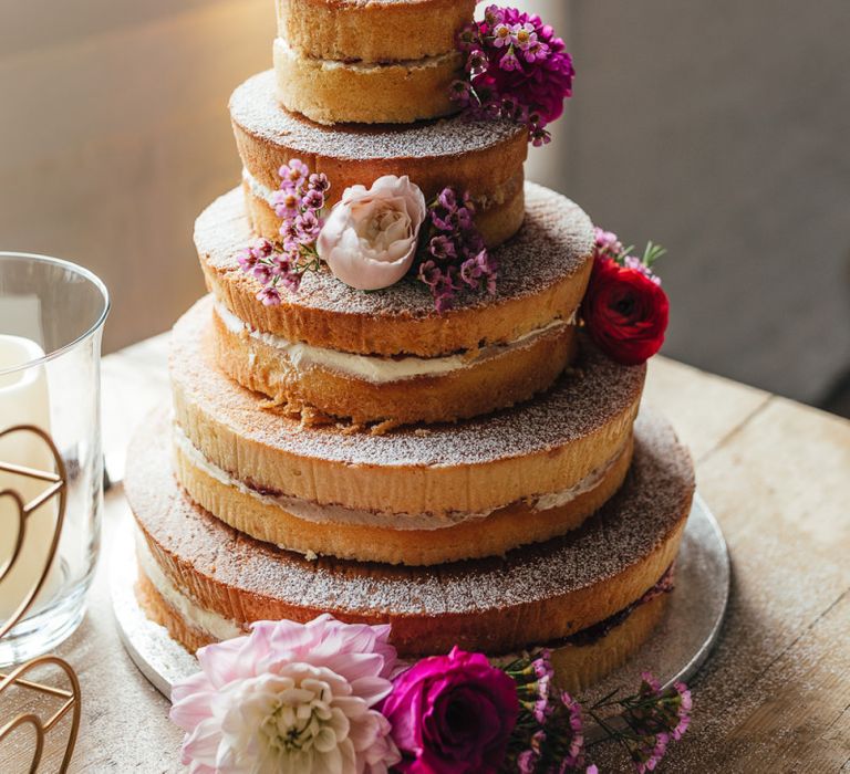 Five tier cake with pink floral decorations at industrial styled reception in London