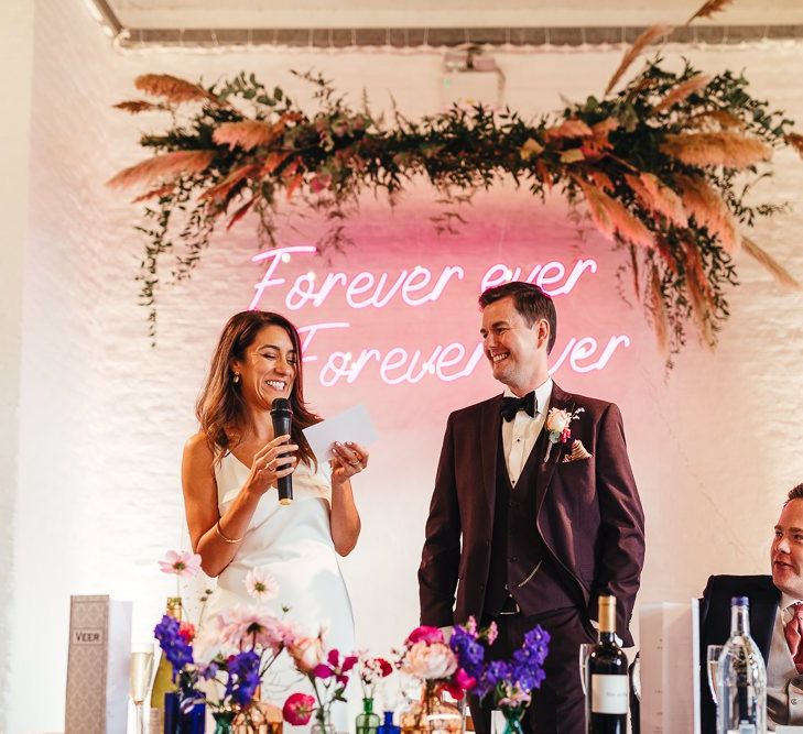 Pink neon sign and vibrant florals at dry hire wedding venue