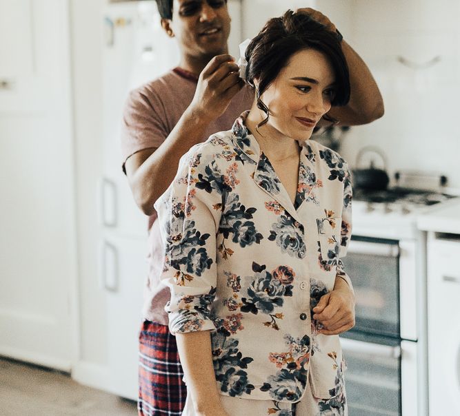 Groom helping his bride with her hair on the wedding morning