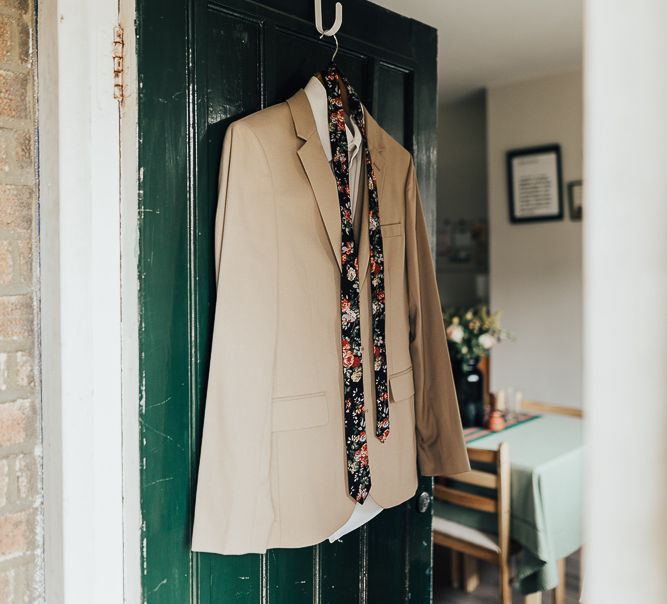 Grooms beige wedding suit and floral tie