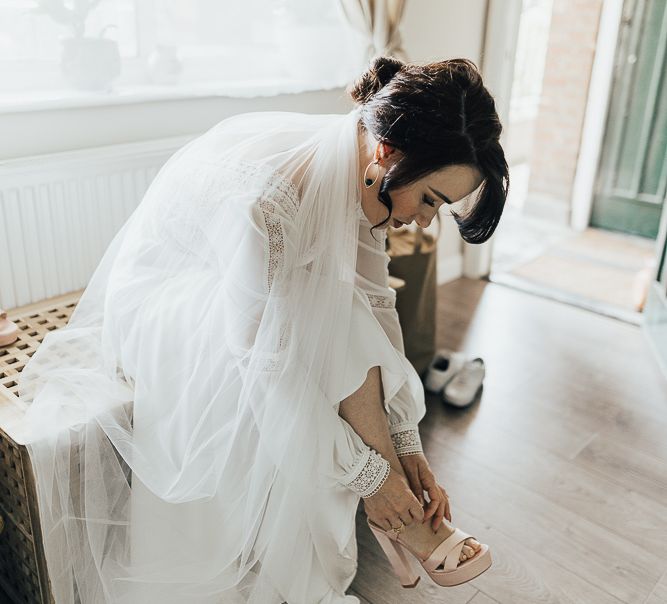 Bride in Rosa Clara wedding dress putting on her wedding shoes