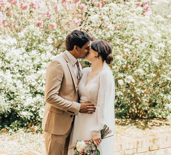 Bride and groom kissing in front of blossom tree