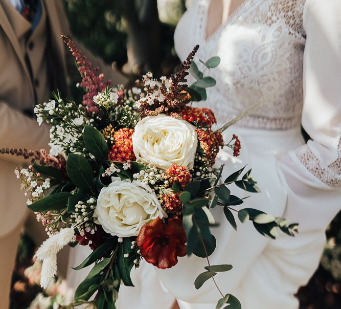 White rose bouquet with red filler flowers and green foliage