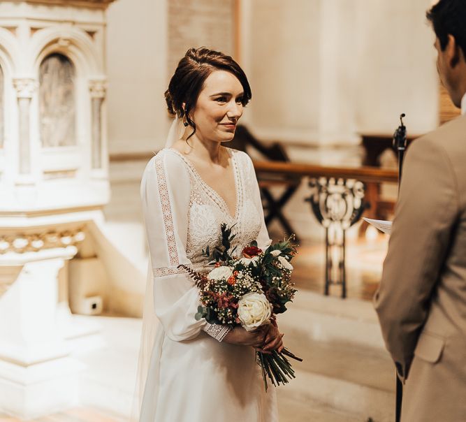 Bride standing at the altar in Rosa Clara wedding dress with long sleeves