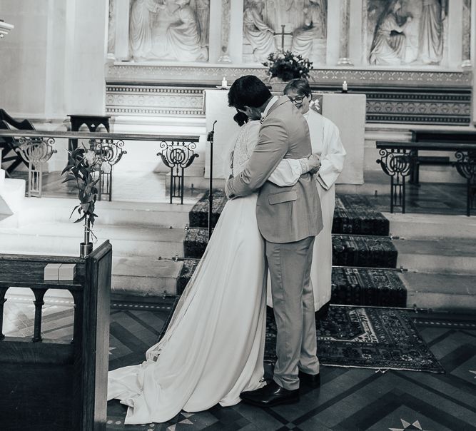 black and white portrait on bride and groom embracing  at the altar