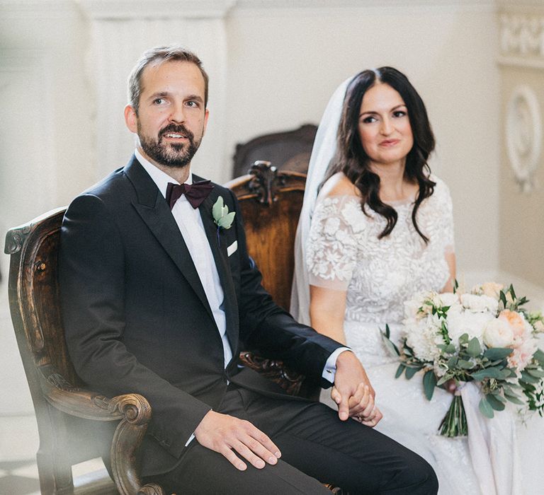 Wedding Ceremony | Bride in Hermione de Paula Wedding Gown with Short Sleeves and Personalised Embroidery | Cathedral Veil | Groom in Navy Lanvin Tuxedo and Black Burberry Shoes | Burgundy Bow Tie | Blush, Cream and Pink Bridal Bouquet | Stunning Syon Park Wedding with Quill Stationery Suite | Nancy Ebert Photography