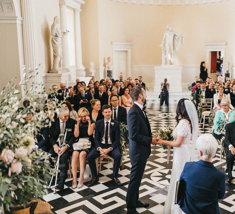 Wedding Ceremony | Bride in Hermione de Paula Wedding Gown with Short Sleeves and Personalised Embroidery | Cathedral Veil | Groom in Navy Lanvin Tuxedo and Black Burberry Shoes | Burgundy Bow Tie | Blush, Cream and Pink Bridal Bouquet | Stunning Syon Park Wedding with Quill Stationery Suite | Nancy Ebert Photography