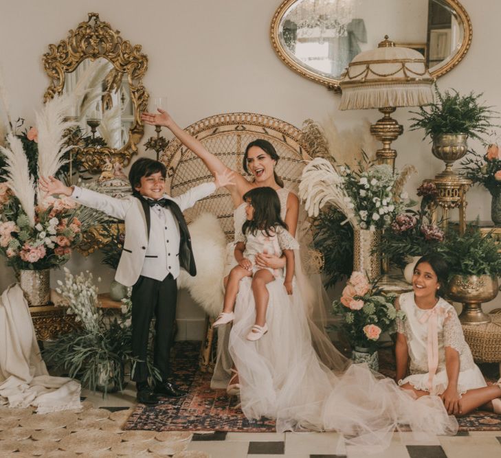 Bride on the Wedding Morning with Her Children Surrounded by Pink and White Flowers with Foliage and Pampas Grass