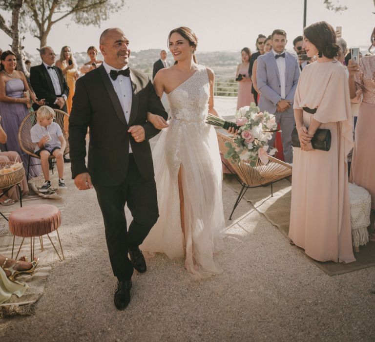 Bride Walking Down the Aisle in a Shimmering One Shoulder Wedding Dress with Side Split