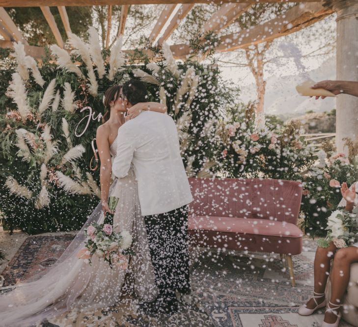 Bride and Groom Kissing During the Confetti Moment at the Altar