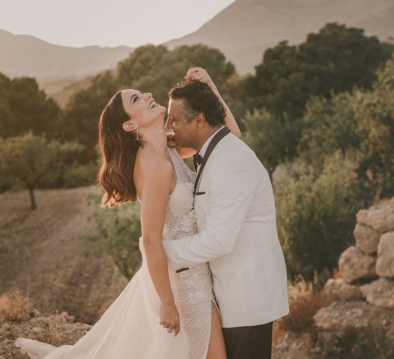 Groom in White Dinner Jacket Kissing His Bride in a Beaded Wedding Dress