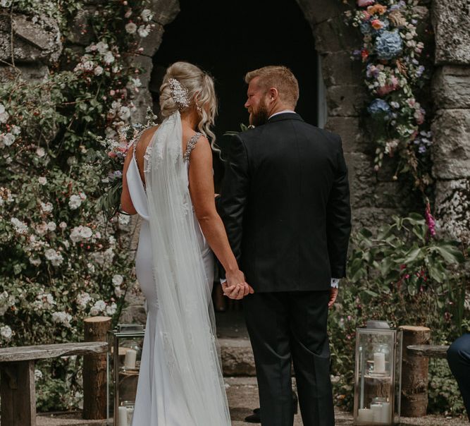 Bride and Groom at altar with pastel flower decor and embroidered veil