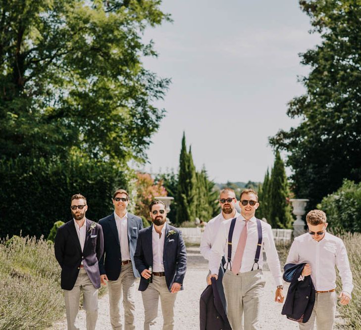 Groom in Navy Jacket, Grey Trousers and White Shirt with Pink Tie from Suit Supply | Outdoor Seating Area and Macaroon Tower at French Chateau Wedding | Lush Imaging