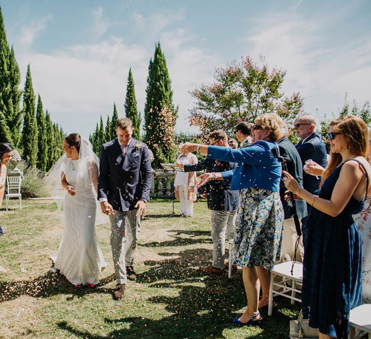 Bride in Lace Boat Neck Pronovias Wedding Dress with Keyhole Back and Fishtail Train | Fingertip Length Veil | Groom in Navy Jacket, Grey Trousers and White Shirt with Pink Tie from Suit Supply | Outdoor Wedding Ceremony at Chateau La Durantie, Dordogne | Outdoor Seating Area and Macaroon Tower at French Chateau Wedding | Lush Imaging