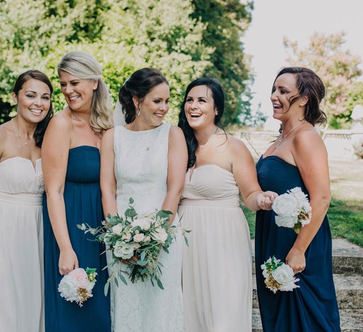 Bride in Lace Boat Neck Pronovias Wedding Dress with Keyhole Back and Fishtail Train | Fingertip Length Veil | Bridal Bouquet of Blush and White Flowers with Foliage | Bridesmaids in Strapless Navy or Pink Dresses from ASOS | Bridesmaid Posies of Pink and White Flowers | Outdoor Seating Area and Macaroon Tower at French Chateau Wedding | Lush Imaging