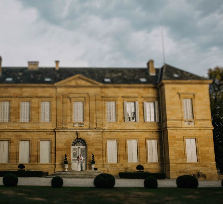 Chateau La Durantie, Dordogne | Bride in Lace Boat Neck Pronovias Wedding Dress with Keyhole Back and Fishtail Train | Groom in Grey Trousers and White Shirt from Suit Supply | Outdoor Seating Area and Macaroon Tower at French Chateau Wedding | Lush Imaging