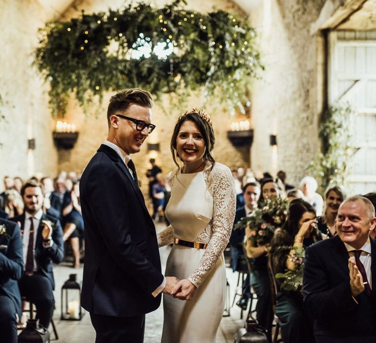 Bride and Groom Standing at Stone Barn Wedding Ceremony Holding Hands Laughing