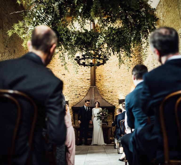 Bride and Groom Standing at The Altar of Stone Barn Wedding Venue in the Cotswolds