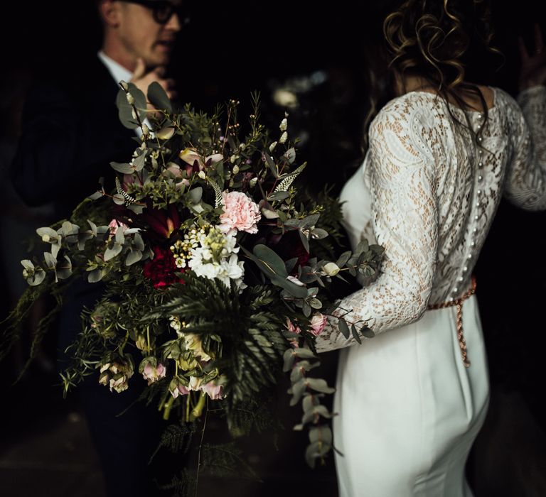 Bride in Lace Back Wedding Dress Holding Her Oversized Foliage Wedding Bouquet