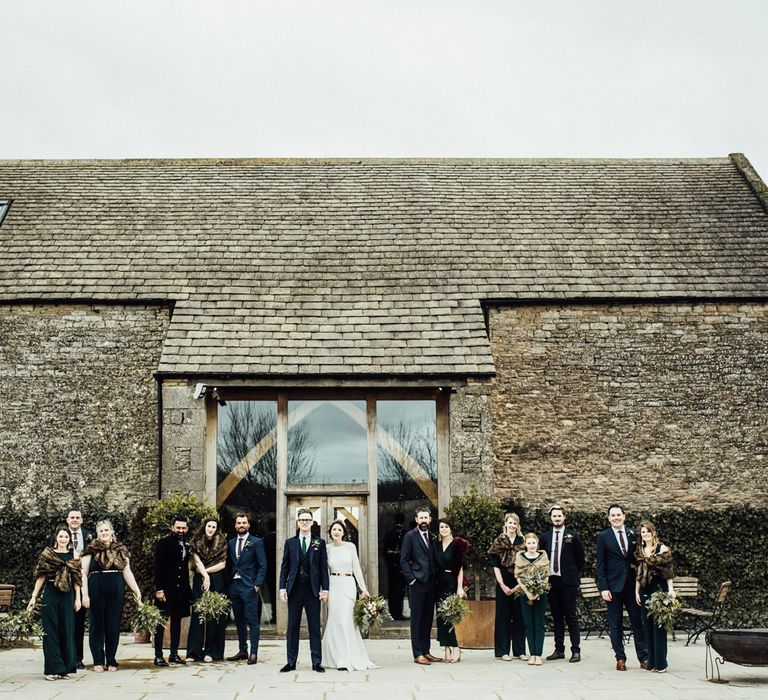 Winter Wedding Party Portrait Standing in Front  of Stone Barn Wedding Venue in the Cotswolds