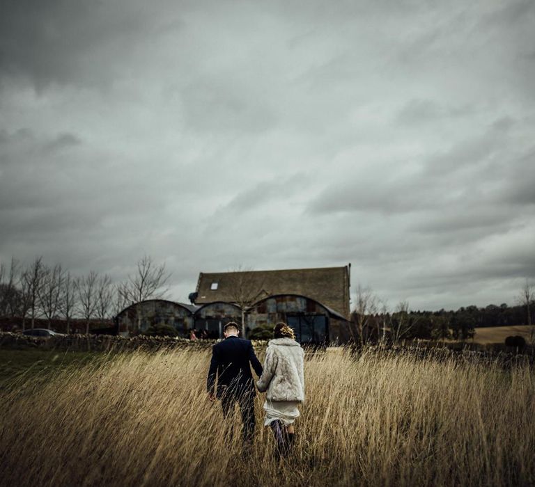 Bride and Groom Holding Hands Walking Through the Fields