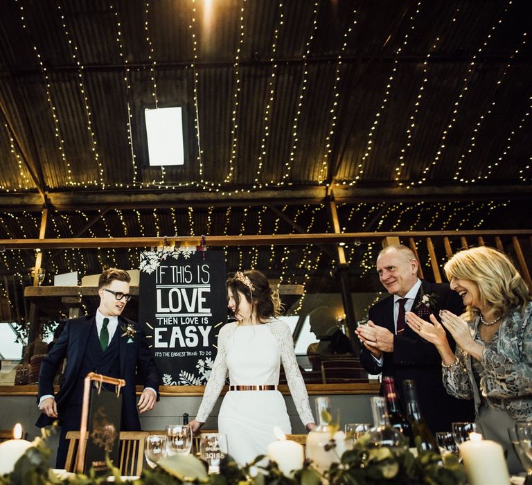 Bride and Groom Talking Their Top Table Seats at Stone Barn Cotswolds with Fairy Light Covered Ceiling