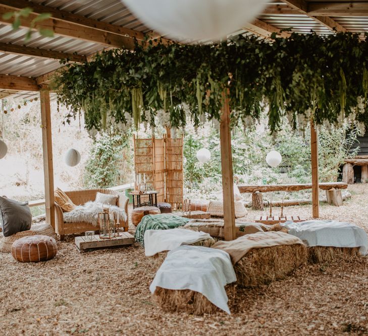 Hay bale Seating Area with Greenery installation | Macramé &amp; Dreamcatcher Woodland Wedding at Upthorpe Wood | Camilla Andrea Photography