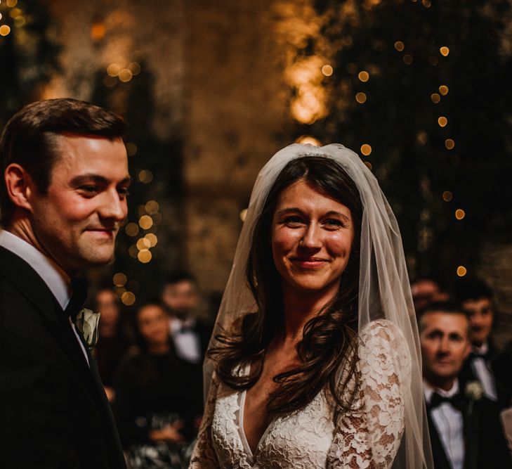 Groom in Black Tie Suit and Bride in Made with Love Bridal Wedding Dress and Veil During Wedding Ceremony