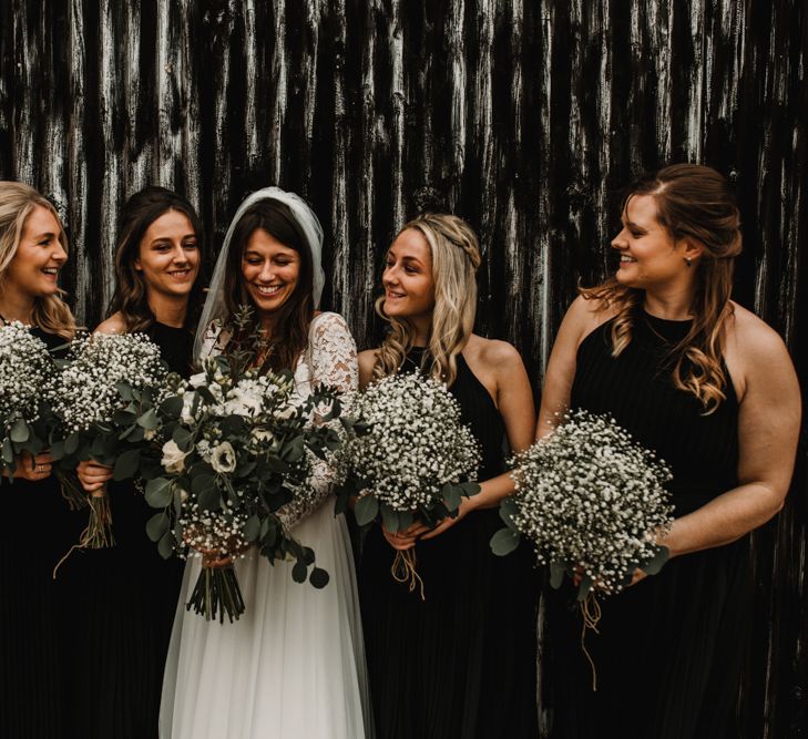 Bridal Party Portrait with Bridesmaids in Black Halter Neck Dresses Holding Gypsophila Bouquets and Bride in Made with Love Bridal Wedding Dress