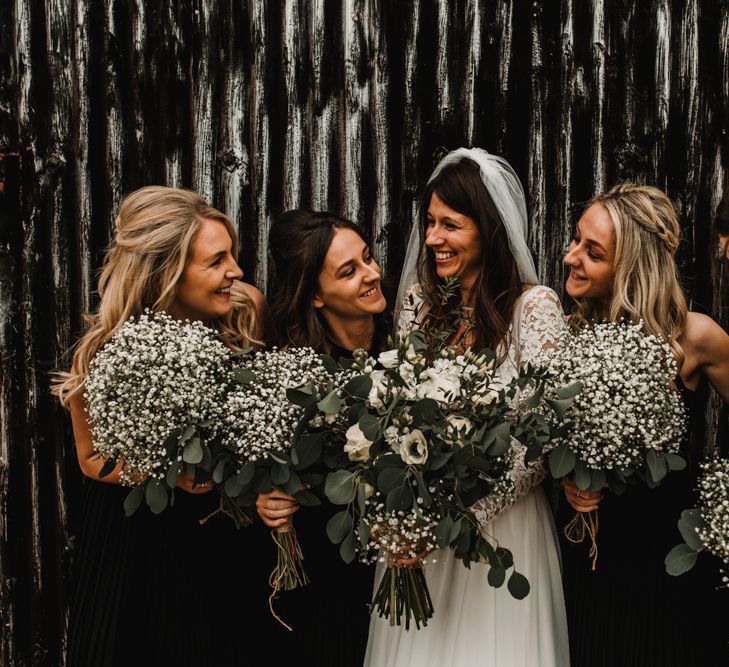 Bridal Party Portrait with Bridesmaids in Black Halter Neck Dresses Holding Gypsophila Bouquets and Bride in Made with Love Bridal Wedding Dress