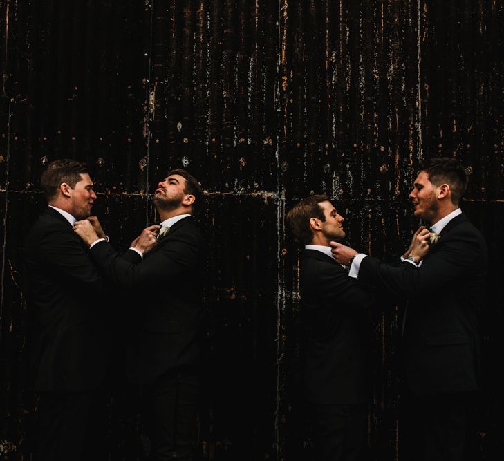 Groomsmen in Black Tie Suits Adjusting Each Others Bow Ties