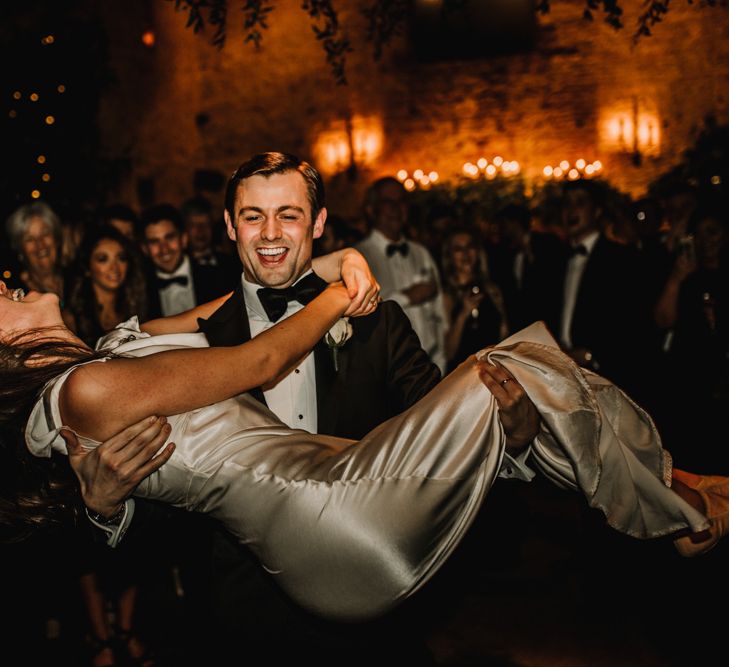 Groom Picking Up His Bride in Satin Wedding Dress During The First Dance