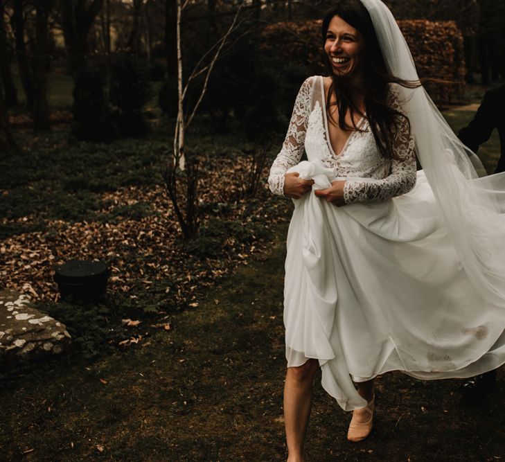 Groom in Tuxedo Holding Up his Brides Made With Love Bridal Wedding Dress Train