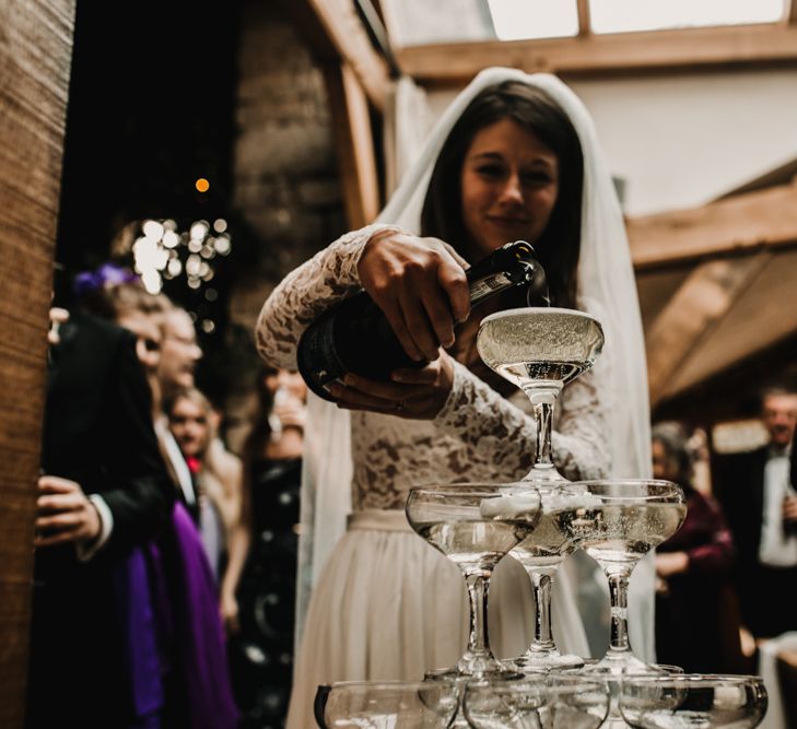 Bride Pouring Champagne Tower in Coupe Glasses