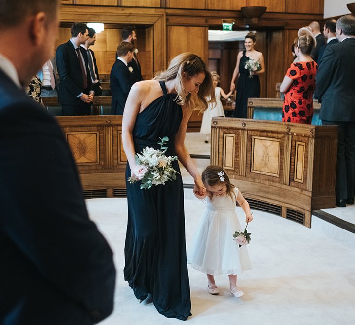 Bridesmaids in Navy Multiway Dresses from Debenhams | Flower Girls in White Dresses | Bouquets of White and Blush Flowers with Foliage | Town Hall Hotel Wedding Ceremony | Statement Floral Arrangement Altar and Potted Plants with Copper Frame Table Plan and Lace Jacket | Miss Gen Photography