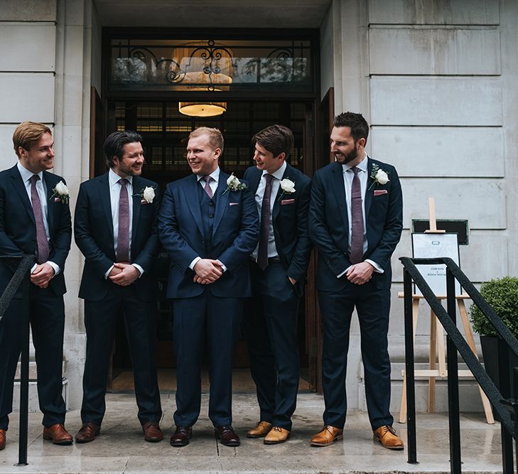 Groom in Navy Three-Piece Suit with Blush Pocket Square | Groomsmen in Navy Two-Pieve Suits | Town Hall Hotel Wedding | Statement Floral Arrangement Altar and Potted Plants with Copper Frame Table Plan and Lace Jacket | Miss Gen Photography