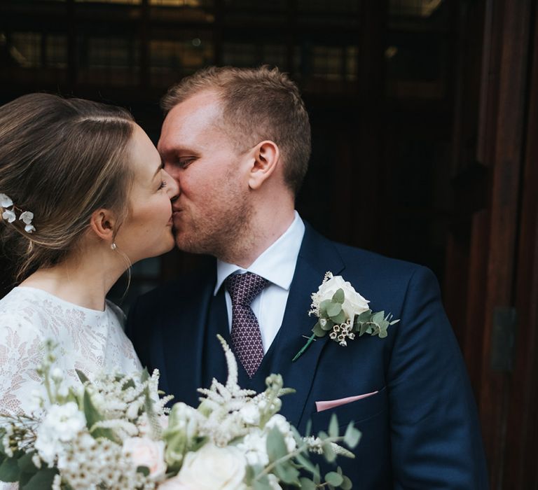 Bride in Charlie Brear Carenne Dress with Spaghetti Straps and Flowing Skirt | Bridal Lace Jacket by Charlie Brear | Bouquet of White and Blush Flowers with Foliage | Groom in Navy Three-Piece Suit with Blush Pocket Square | Town Hall Hotel Wedding | Statement Floral Arrangement Altar and Potted Plants with Copper Frame Table Plan and Lace Jacket | Miss Gen Photography