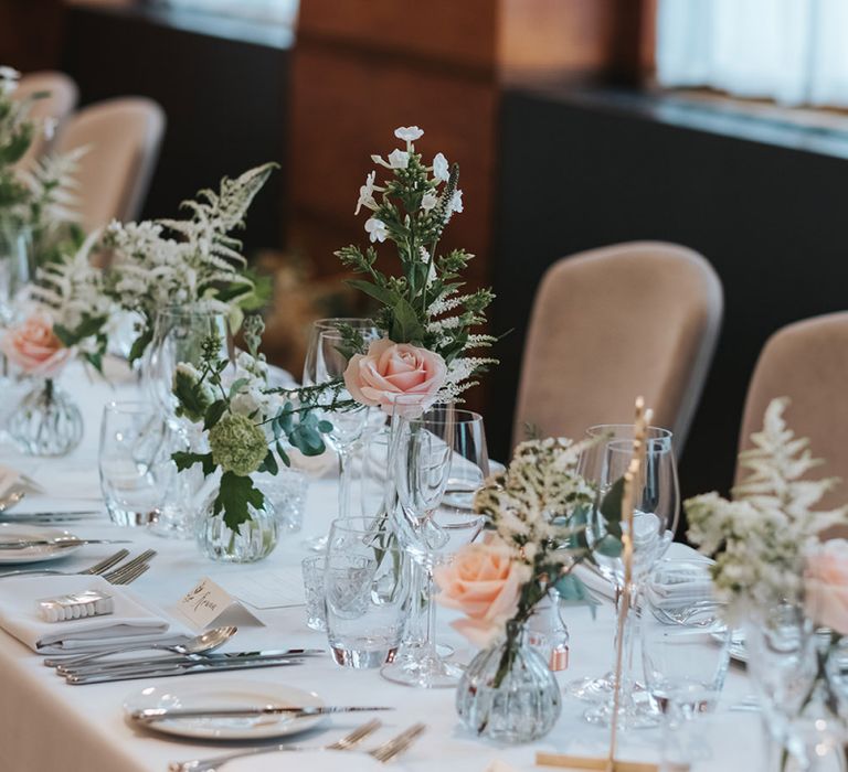 Blush Roses and Foliage in Bud Vases | Gold Calligraphy Table Numbers | Papier Place Cards | Mint Box Favours | Statement Floral Arrangement Altar and Potted Plants with Copper Frame Table Plan and Lace Jacket | Miss Gen Photography