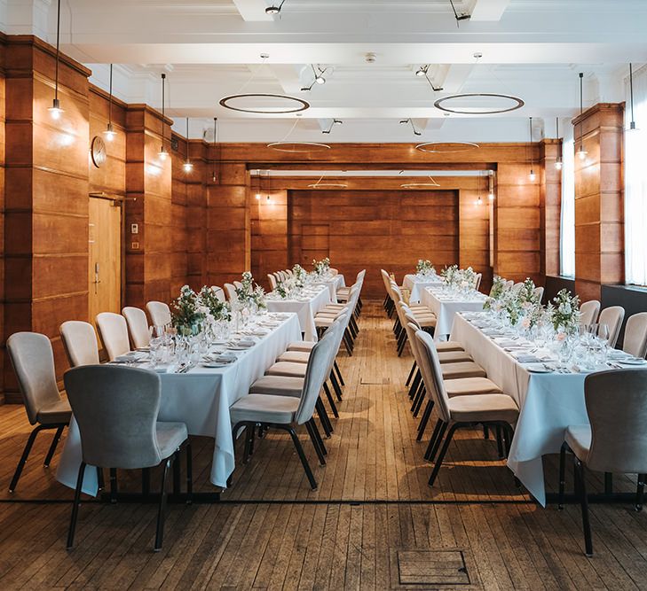 Long Banquet Tables | Grey Chairs | Blush Roses and Foliage in Bud Vases | Wooden-Clad Room at Town Hall Hotel | Statement Floral Arrangement Altar and Potted Plants with Copper Frame Table Plan and Lace Jacket | Miss Gen Photography